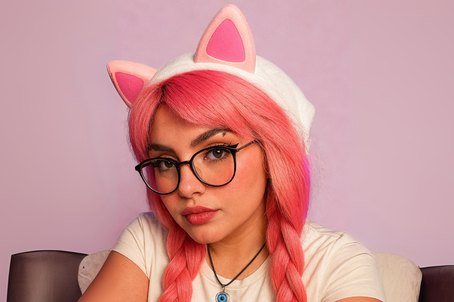 Depiction of Play88Beila with striking pink hair, glasses and blue eye necklace.